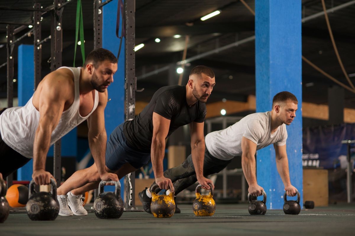 Group of Athletic Men Training Push Ups in Gym. Strong Muscular Athletes During Workout With Kettlebells. Strength Training, Powerlifting and Sports.